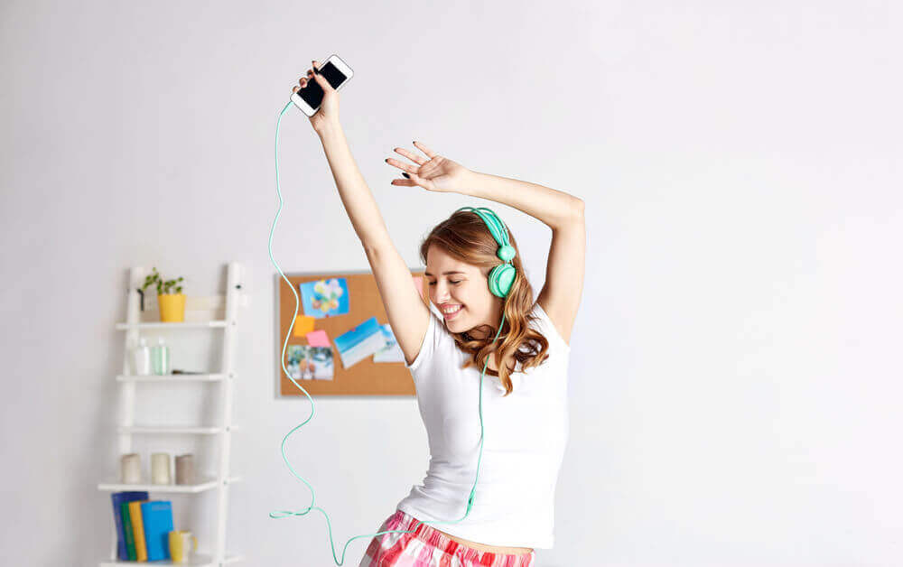 A woman dancing in her home while wearing headphones.