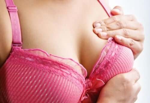 A woman examining her breast for nipple bumps.