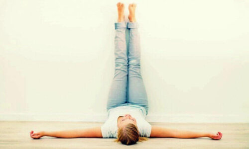 A woman laying on the floor with her feet on the wall.
