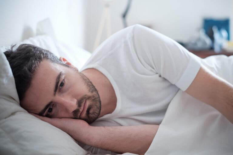 a man laying in bed, sad because of a breakup