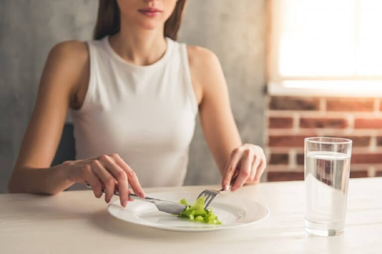 Vrouw die groenten van haar bord eet