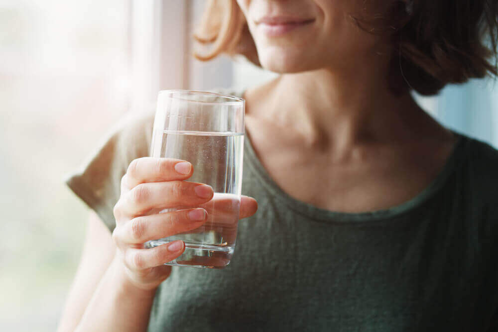 A woman hydrates with a glass of water.