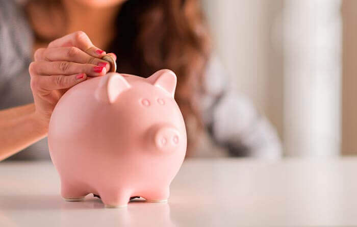 a woman putting money in a piggy bank to save money