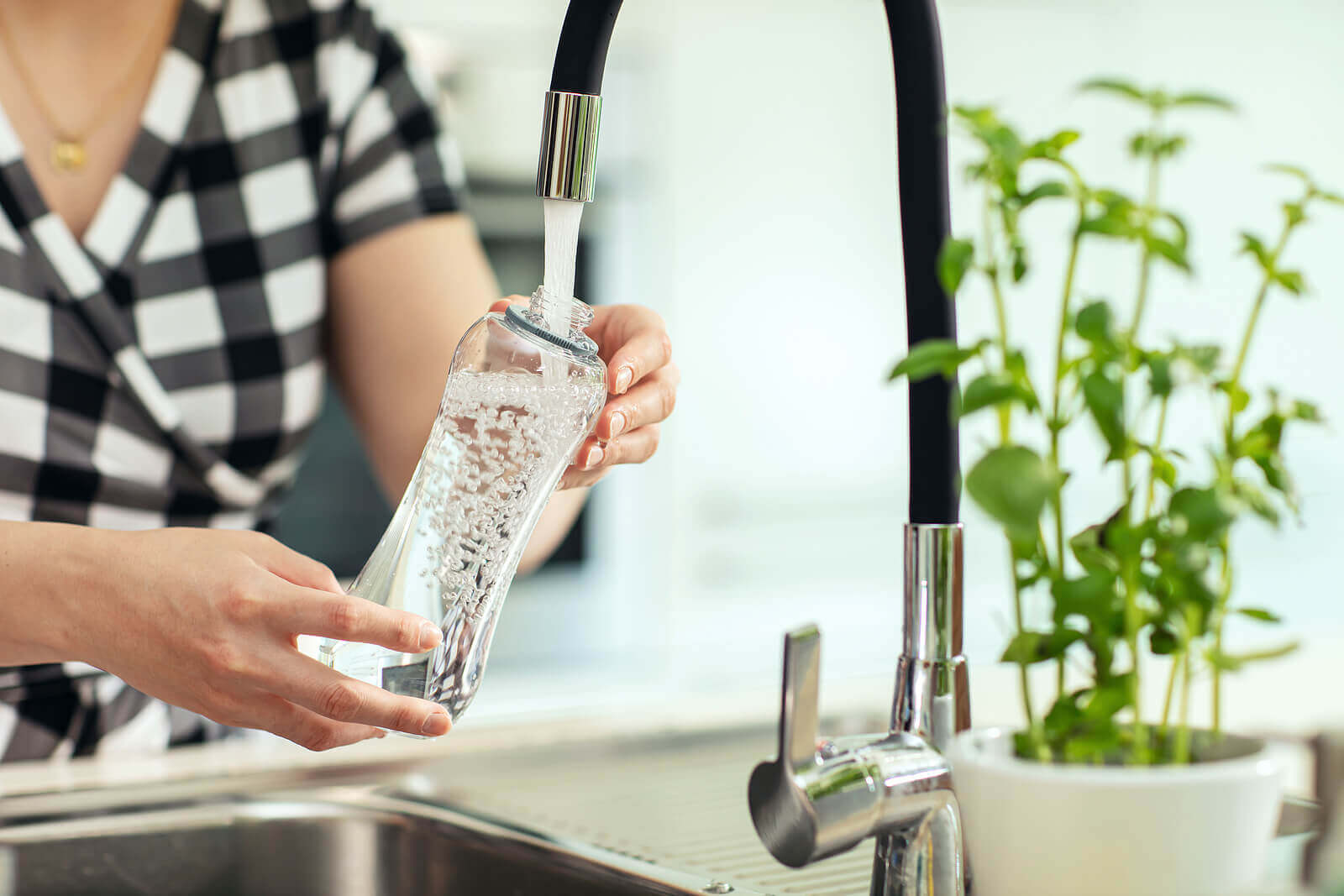A woman filling up a water bottle.