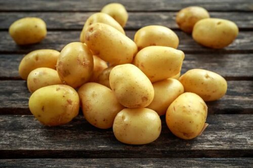 A pile of potatoes on a wooden table.