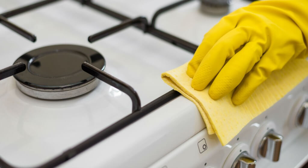A person cleaning their kitchen with yellow gloves.