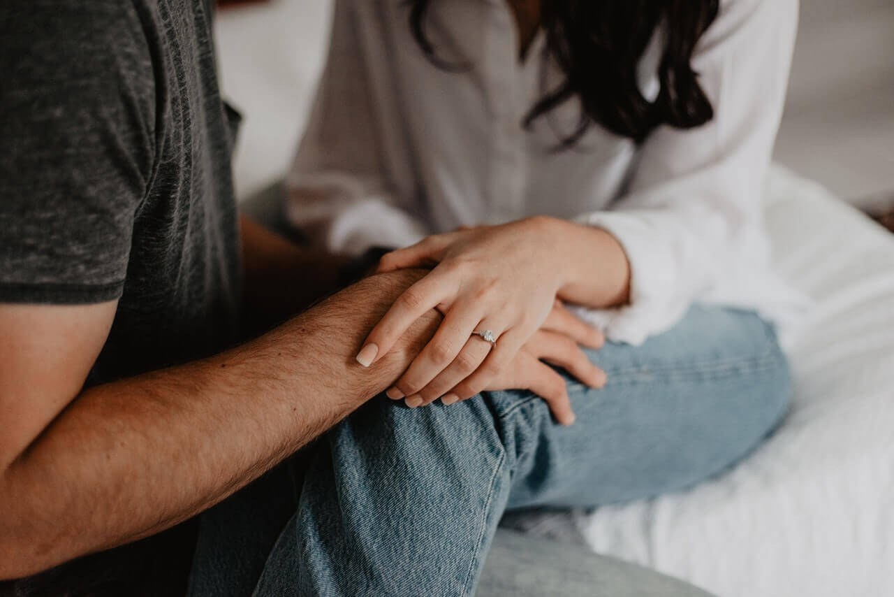 A man and woman sitting close to one another, holding hands.