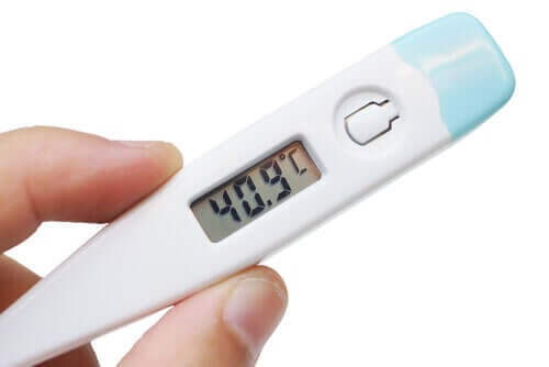 hand holding a digital thermometer; 8 symptoms of pneumonia