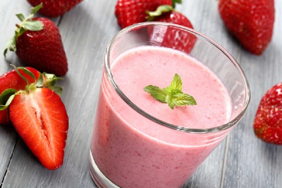A pink beverage with some strawberries.