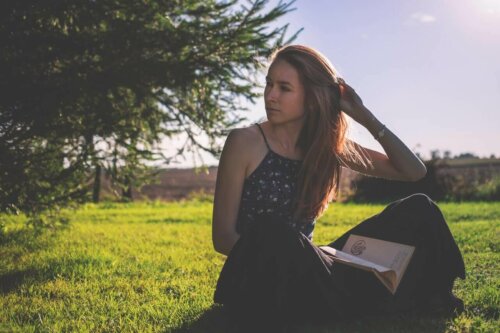 woman reading in a field in the sunshine looking to her right