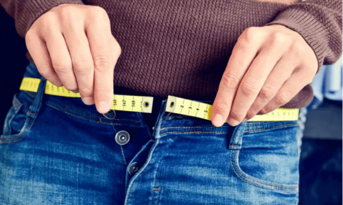 A person measuring their weight thinking about the foods to avoid.