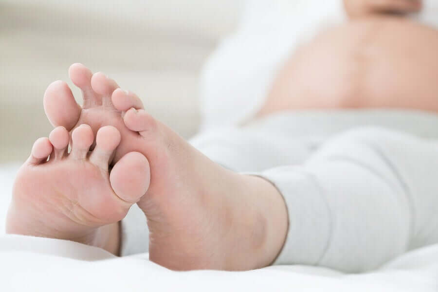 The feet of a pregnant woman who's lying in bed.
