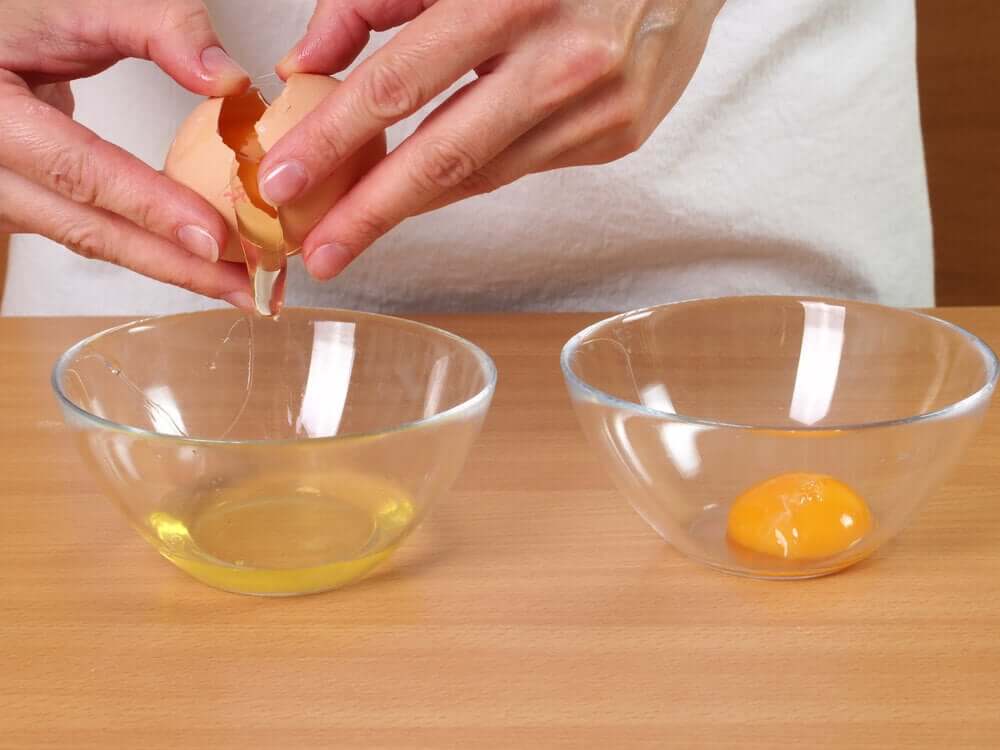 A woman cracking an egg and separating the yolk.