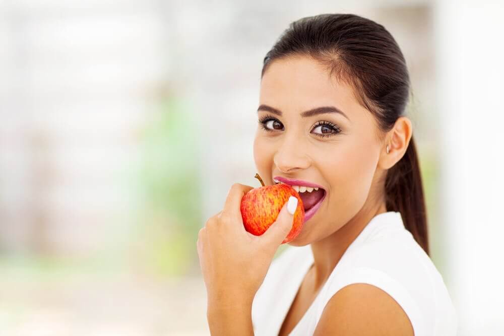 Woman eating an apple supplement to stop smoking