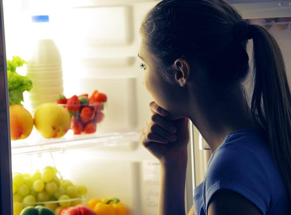 woman deciding what to eat in front of the fridge