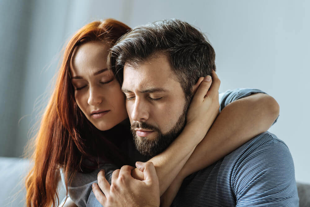 A couple with their eyes closed, embracing.