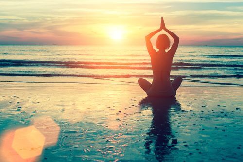 a woman meditating on the beach