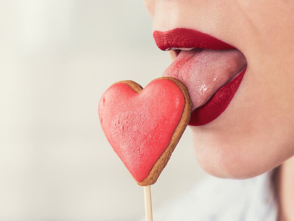 woman sucking on heart-shaped lollipop