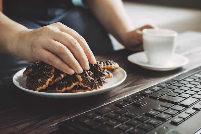 A person eating cookies in front of a computer.