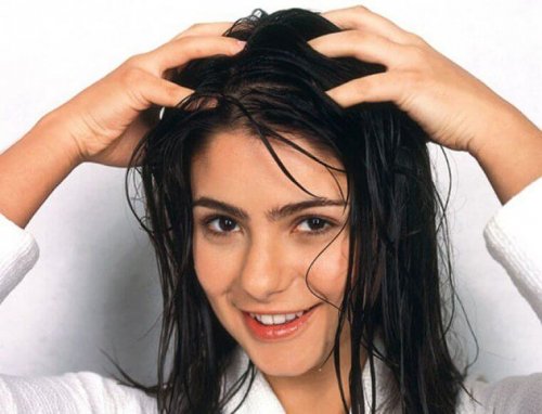 A woman massaging her hair to slow down hair loss.