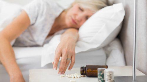 woman sleeping next to sleeping pills