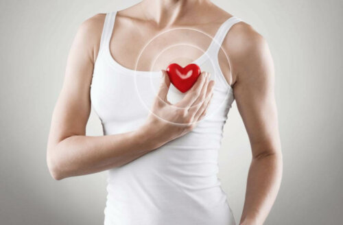Kvinde holder plastikhjerte foran sit eget hjerte