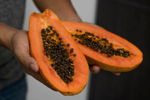 A person showing off the papaya seeds in the fruit.