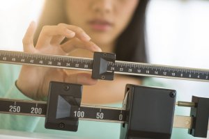 A woman weighing herself to determine her biological age