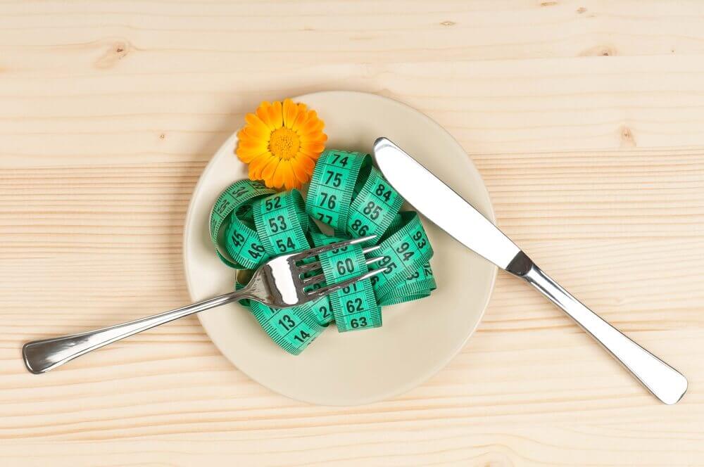 A measuring tape on a plate representing a diet.