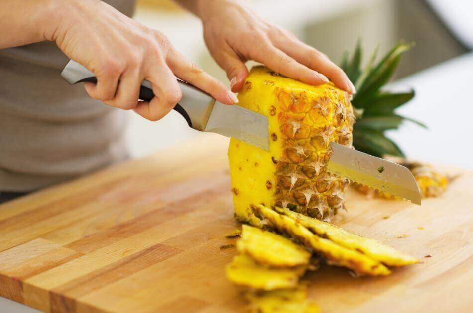 A person cutting a pineapple.