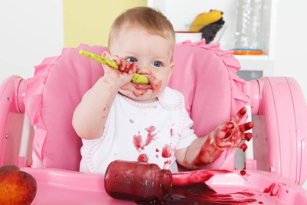 A baby making a mess while eating.