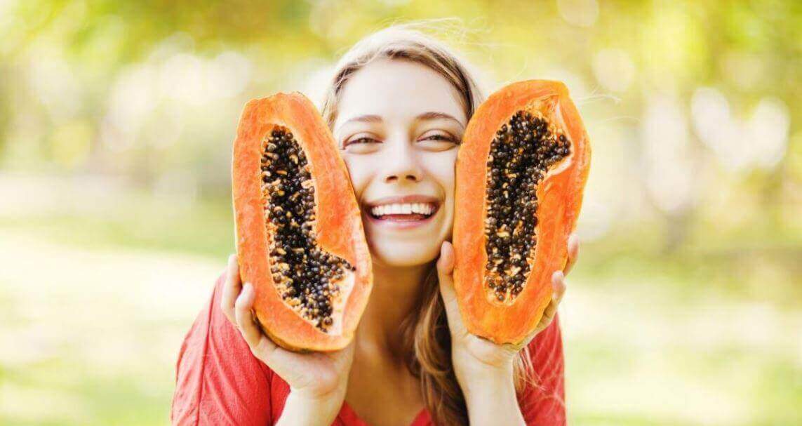 A girl happily holding some papaya.