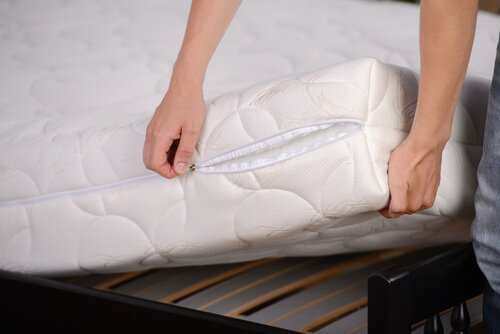 A person changing the mattress cover to disinfect the bedroom.