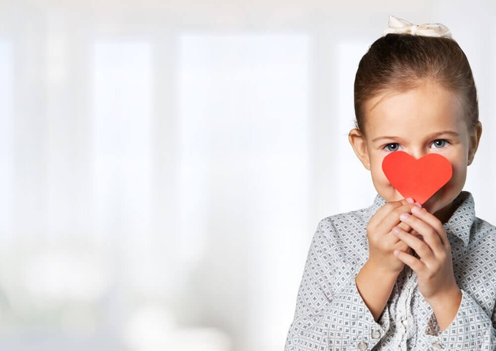 A potential crystal child holding a cardboard heart in front of her face