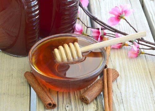 A bowl of honey with cinnamon sticks