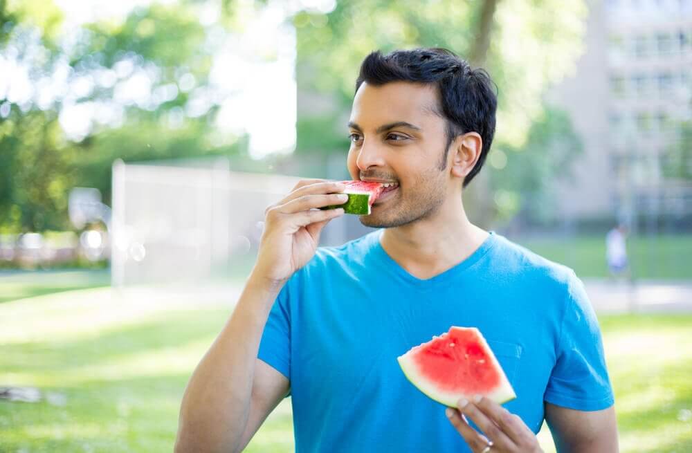 A man eating slices of watermelon