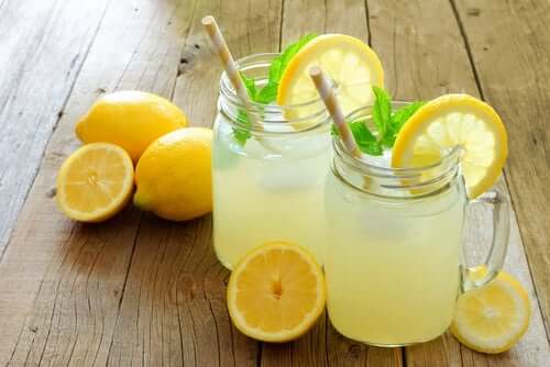 Some lemonade and lemons on a wooden table.