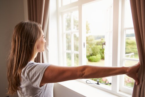 A woman looking out of the window after getting rid of damp smells