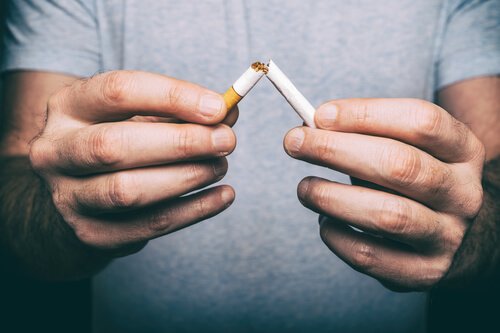 person breaking a cigarette in half