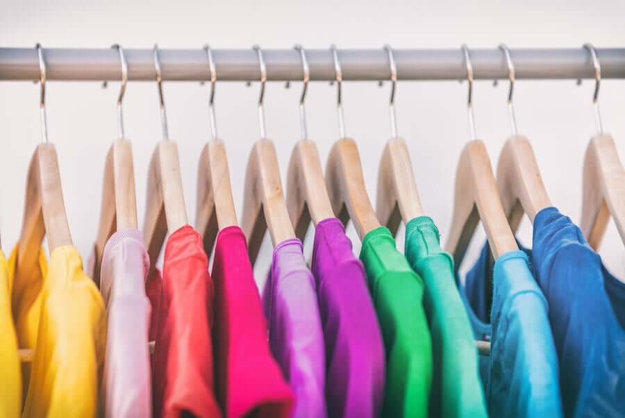 A row of brightly colored shirts on hangers.