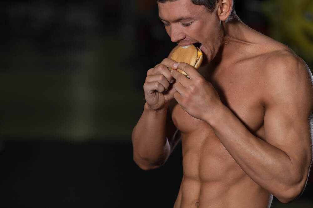 A man eating a hamburger and exercising.