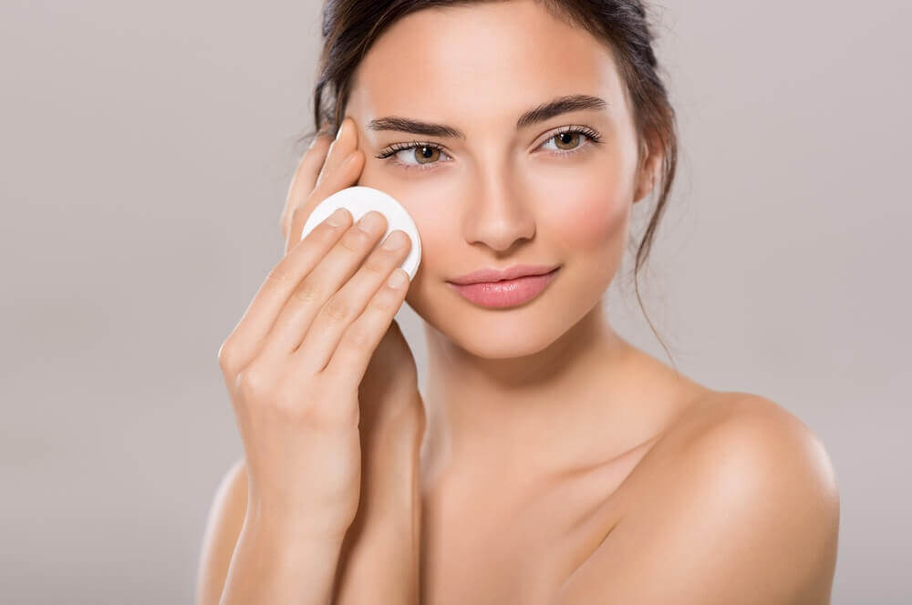 A woman applying some toners to her face.