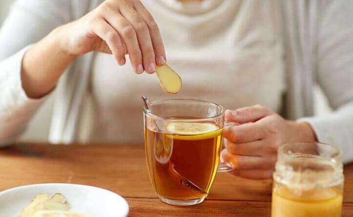 A person drinking a cup of tea with lemon.