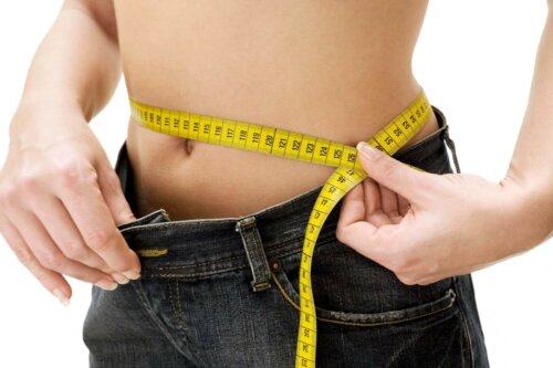 A woman measuring her waistline.