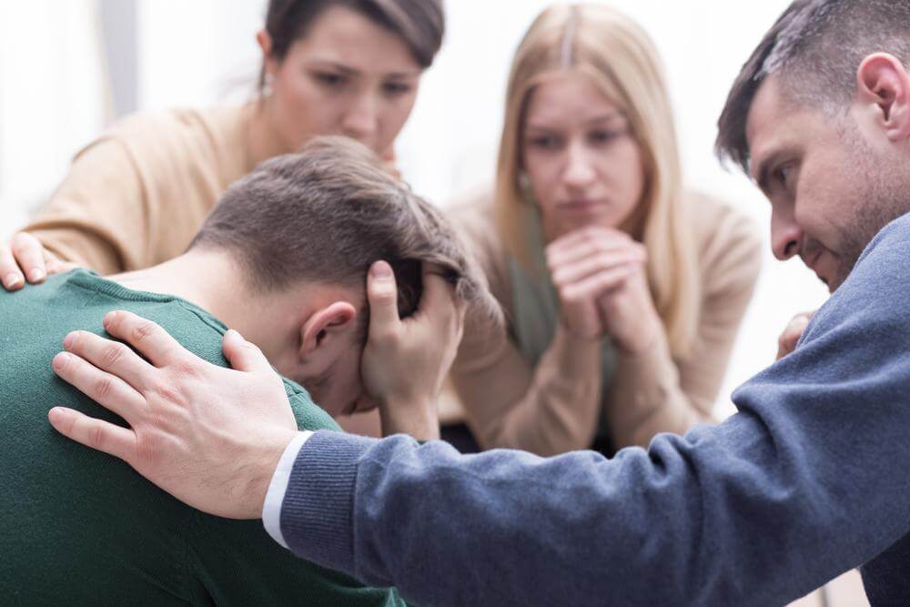 a group of friends consoling a man