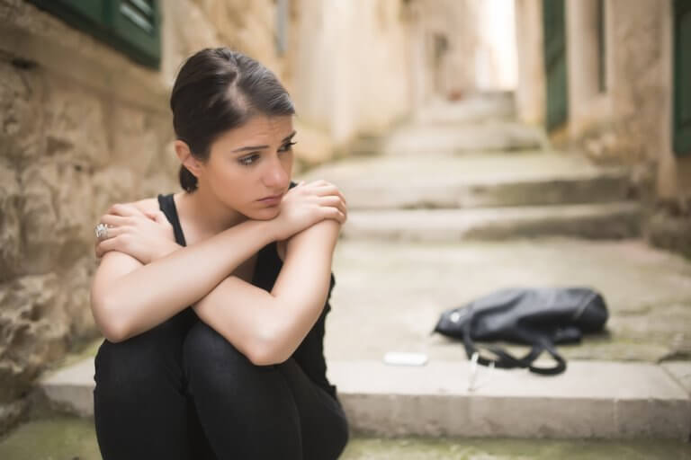 A sad woman alone in the street.