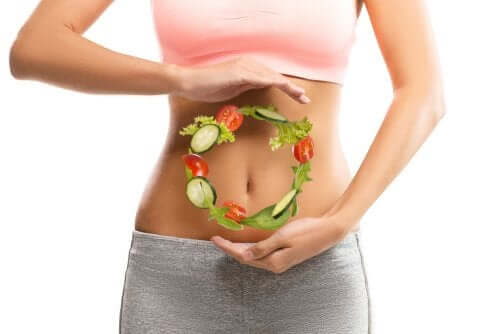 A woman with a circle of vegetables in front of her belly.