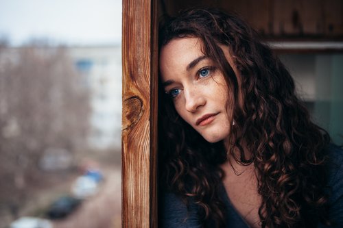 Woman leaning against a wall looking hopeless