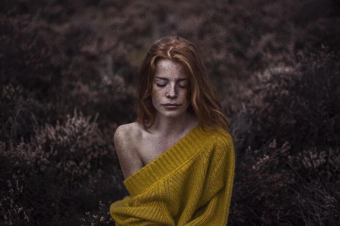 Woman kneeling in a field feeling lonely