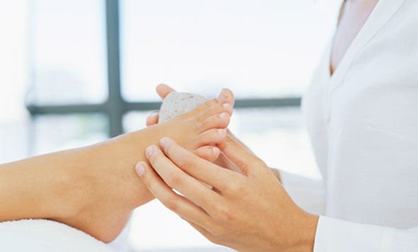 Woman removing foot calluses with a pumice stone